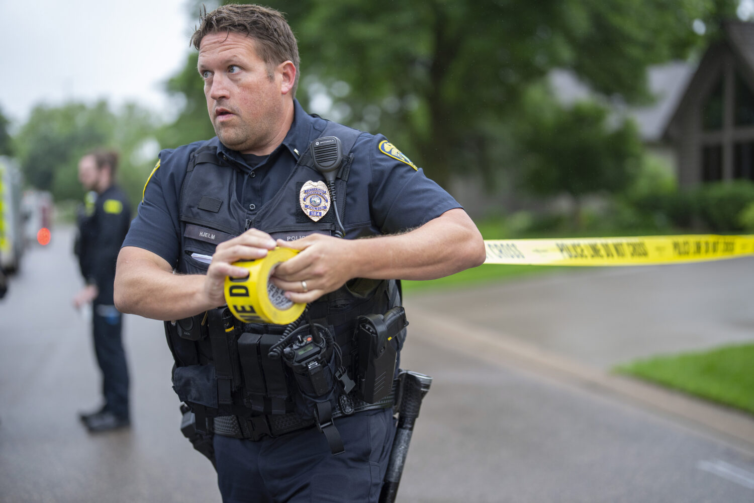 Brooklyn Park Police Lieutenant Hjelm sets up a perimeter with police tape near the scene of a shoo...