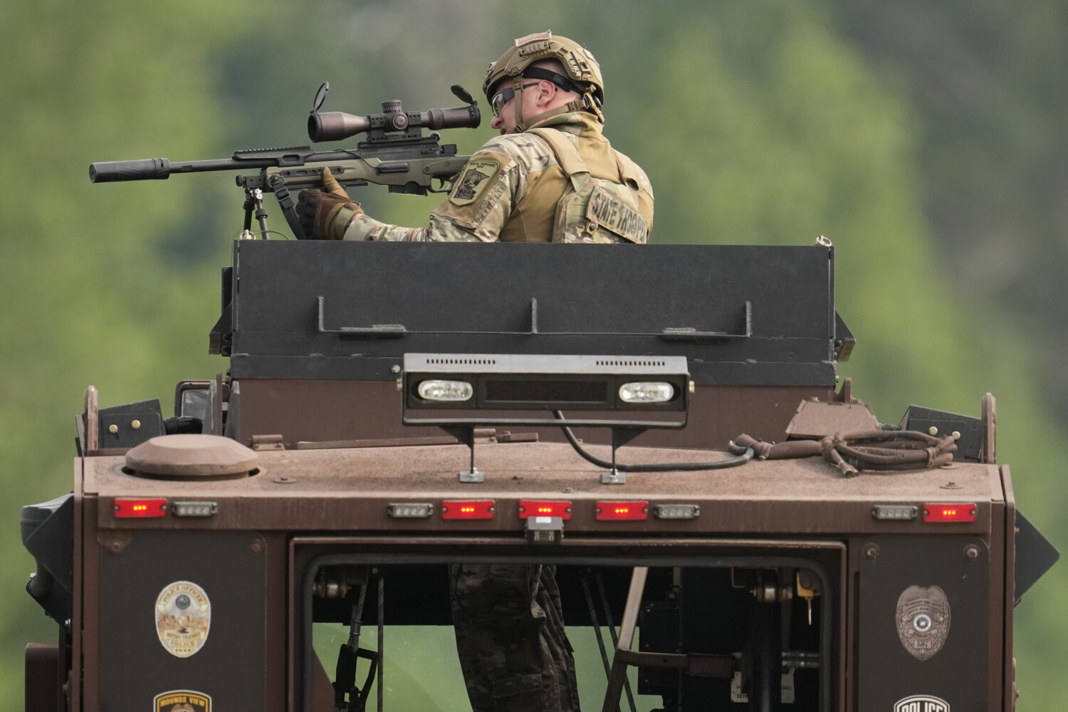 A law enforcement officer trains his rifle towards a house as the officers search for shooting susp...