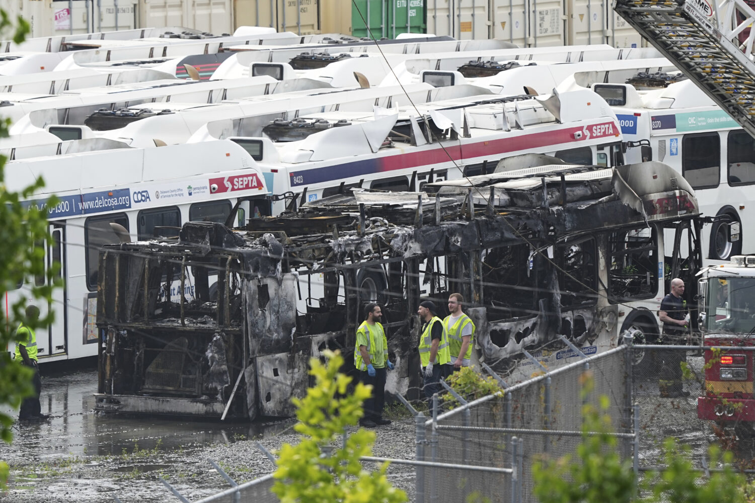 Officials inspect the burnt wreckage of a bus at Southeastern Pennsylvania Transportation Authority...