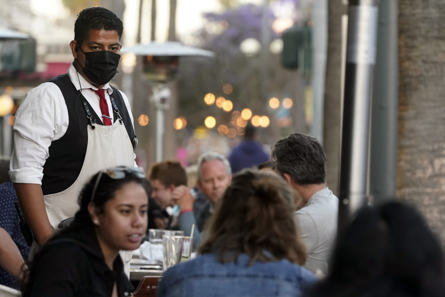 FILE - A server tends to customers in an outdoor dining area on The Promenade in Santa Monica, Cali...