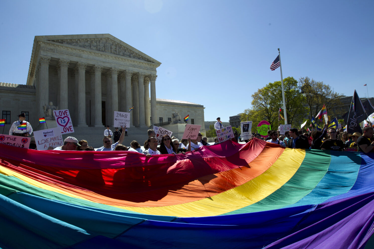 FILE - Demonstrators hold a rainbow pride flag outside the Supreme Court as justices deliberate Obe...