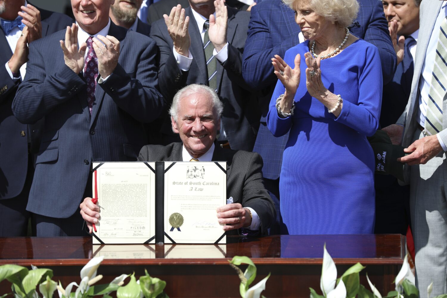 Republican South Carolina Gov. Henry McMaster holds up a ceremonial copy of a bill he signed changi...