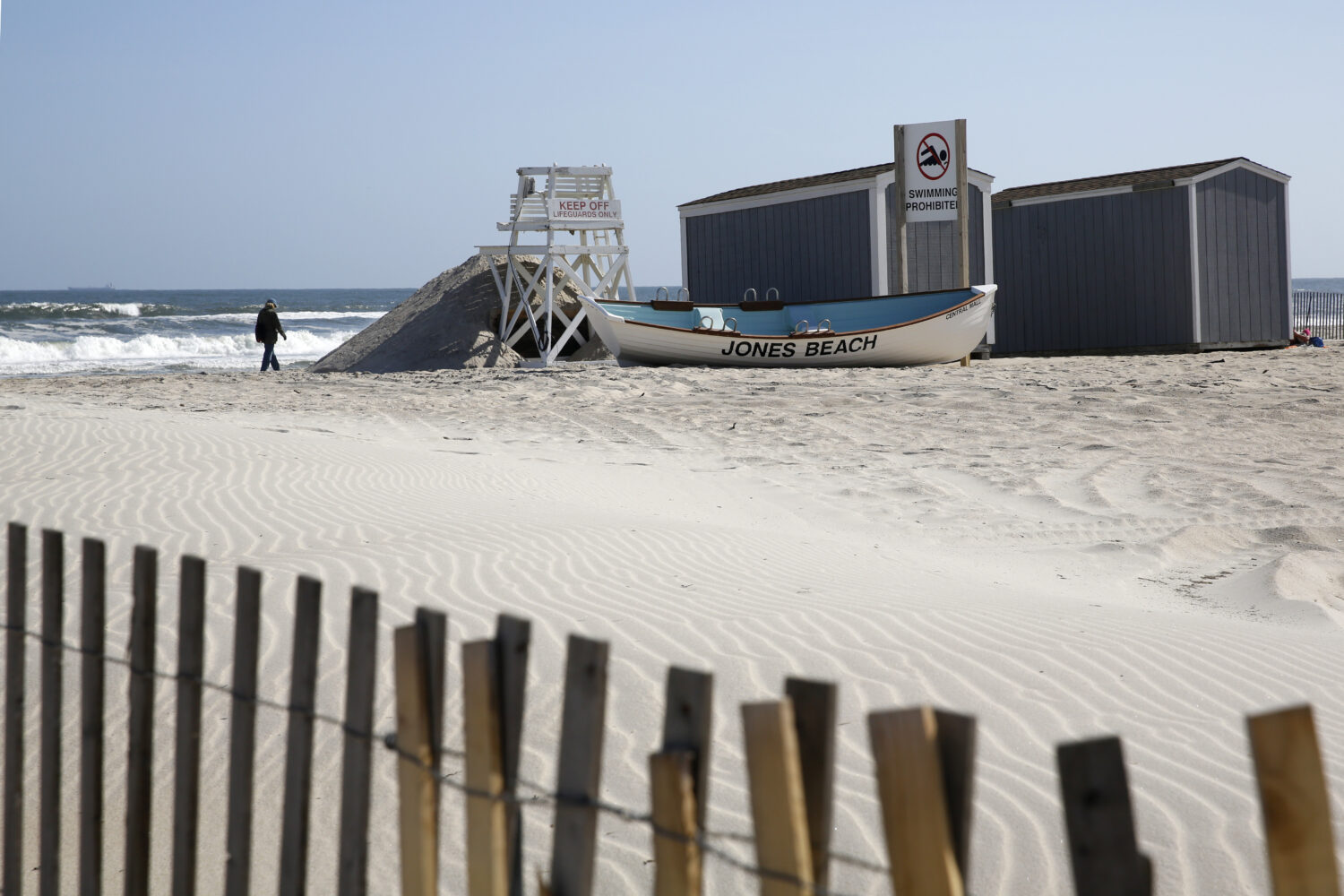 FILE - A person walks by the water at Jones Beach in Wantagh, N.Y., May 21, 2020. (AP Photo/Kathy W...