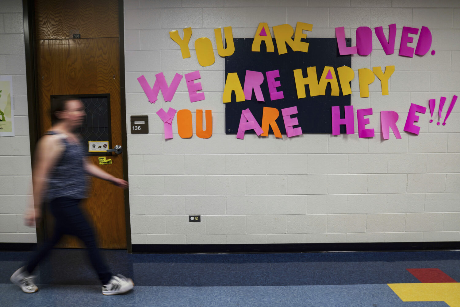FILE - A staff member walks past a message to students that hangs on the wall at Place Bridge Acade...
