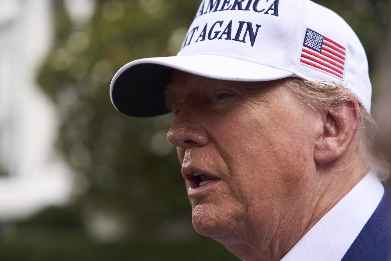 President Donald Trump speaks with reporters as a flag pole is installed on the South Lawn of the W...