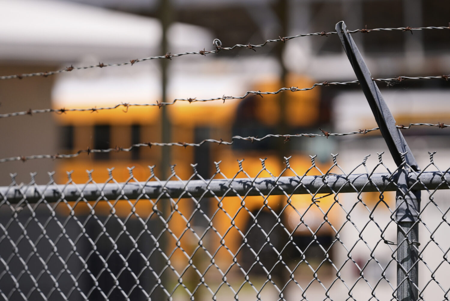 A school bus is seen behind a fence with barbed wire outside Ferriday High School in Ferriday, La.,...