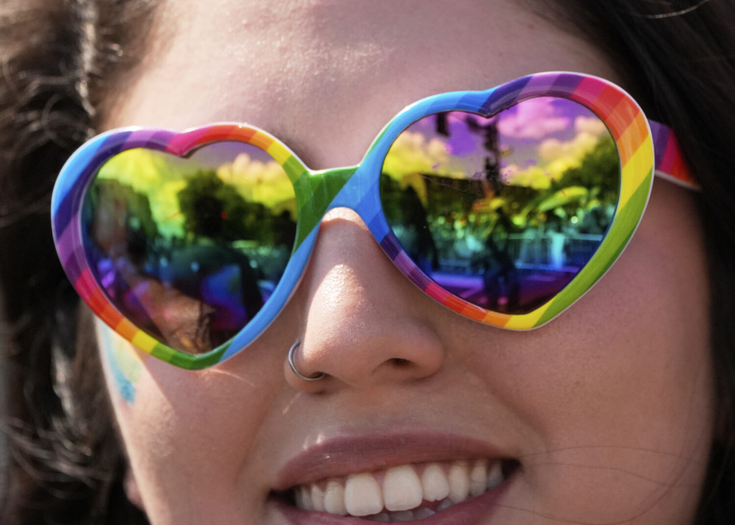 A person wearing rainbow heart sunglasses watches the World Pride parade, Saturday, June 7, 2025, i...