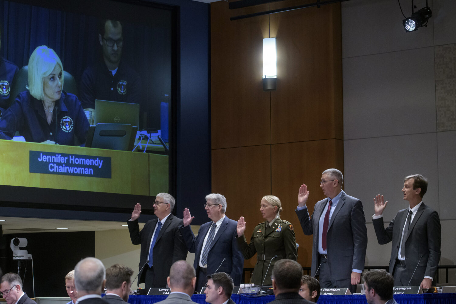 National Transportation Safety Board Chairwoman Jennifer Homendy, on monitor left, swears-in the wi...