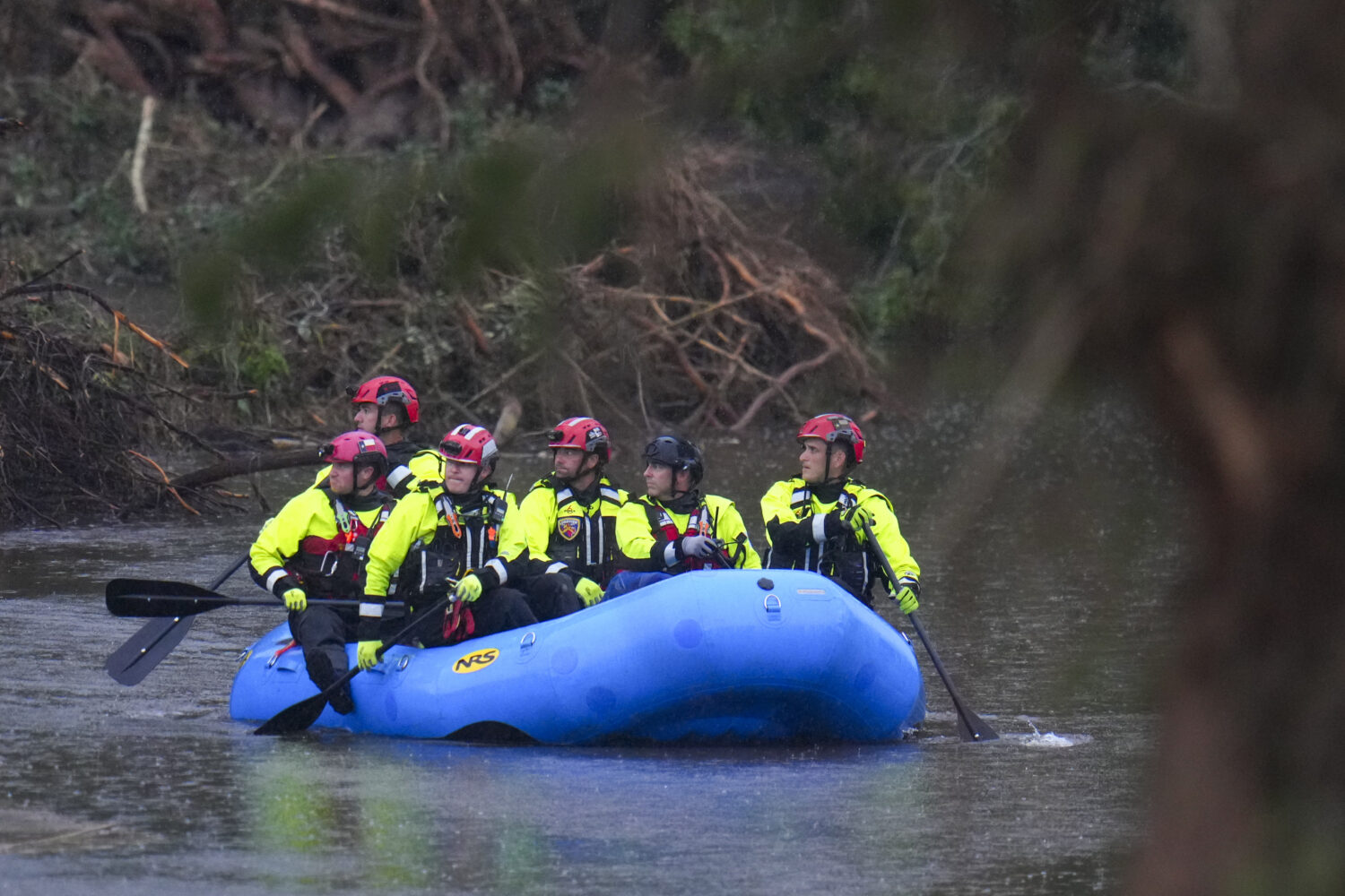 Officials ride a boat as they arrive to assist with a recovery effort at Camp Mystic along the Guad...
