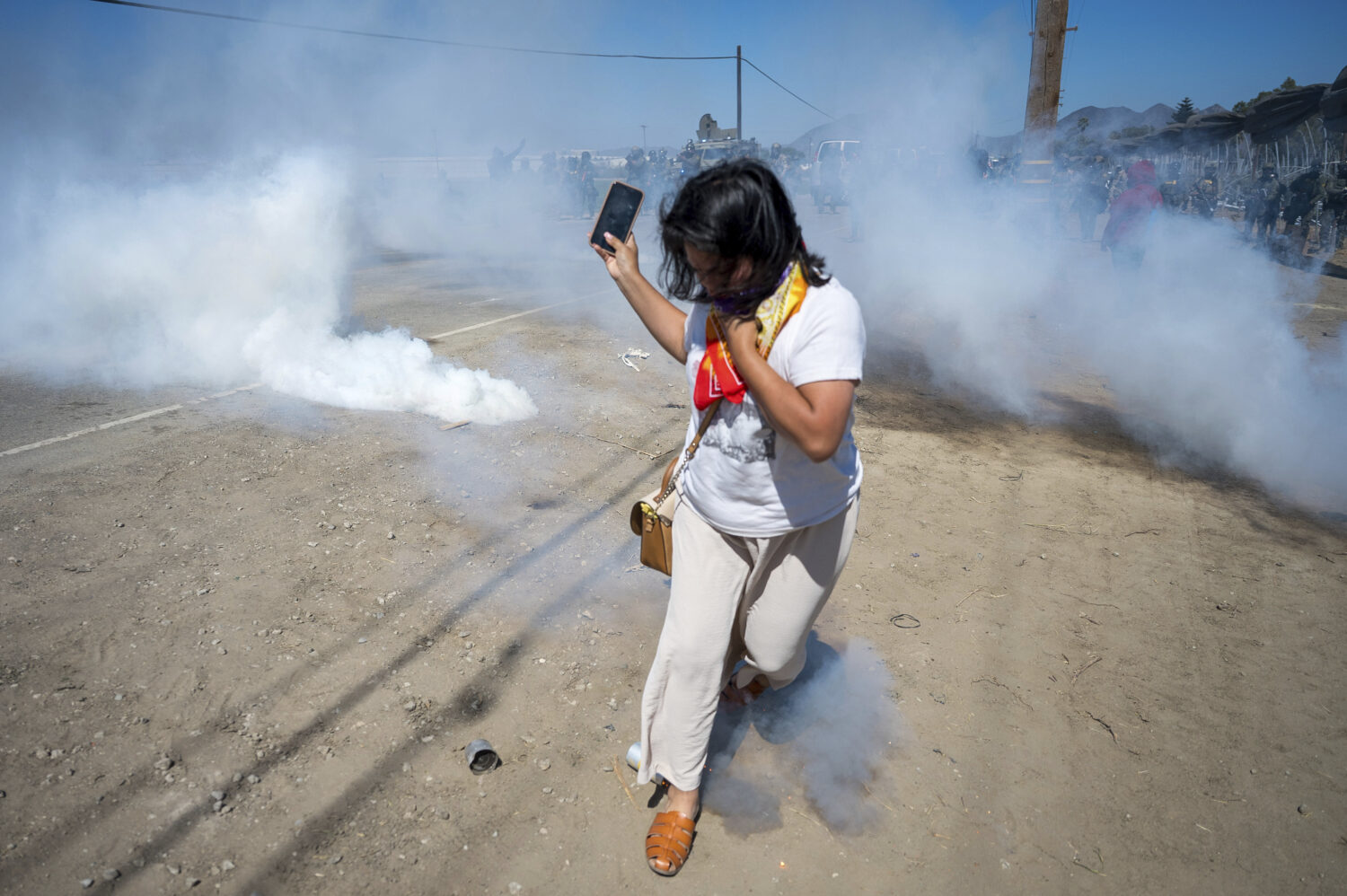 A protester runs from tear gas tossed by federal immigration agents to clear a path for the vehicle...