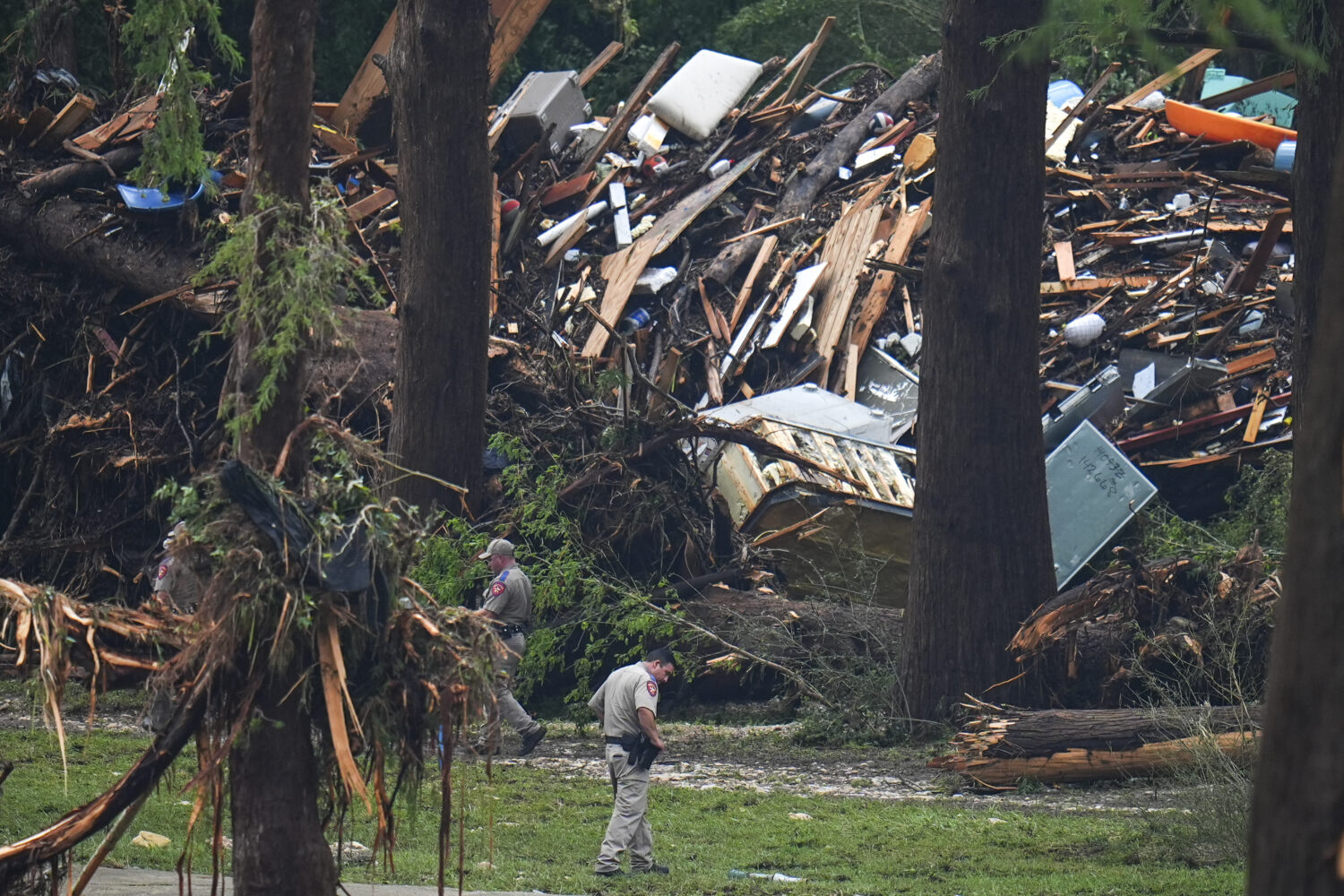 Officials comb through the banks of the Guadalupe River after a flash flood swept through the area ...