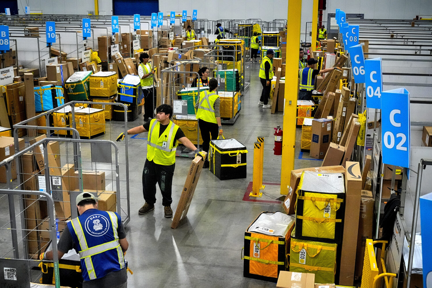 FILE - Amazon employees load packages on carts before being put on to trucks for distribution for A...