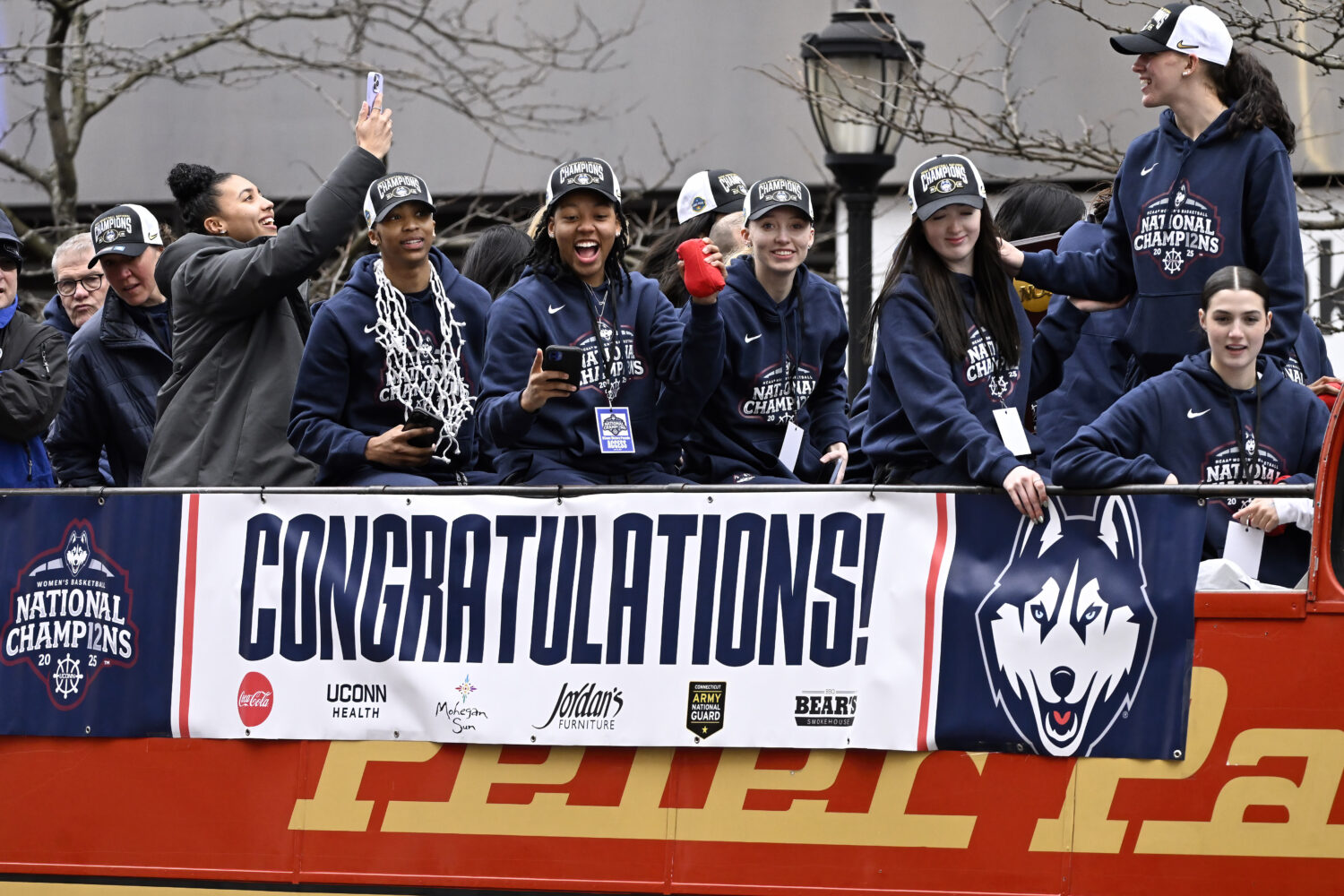 FILE - Members of the UConn women's basketball team celebrate from a bus during a parade celebratin...