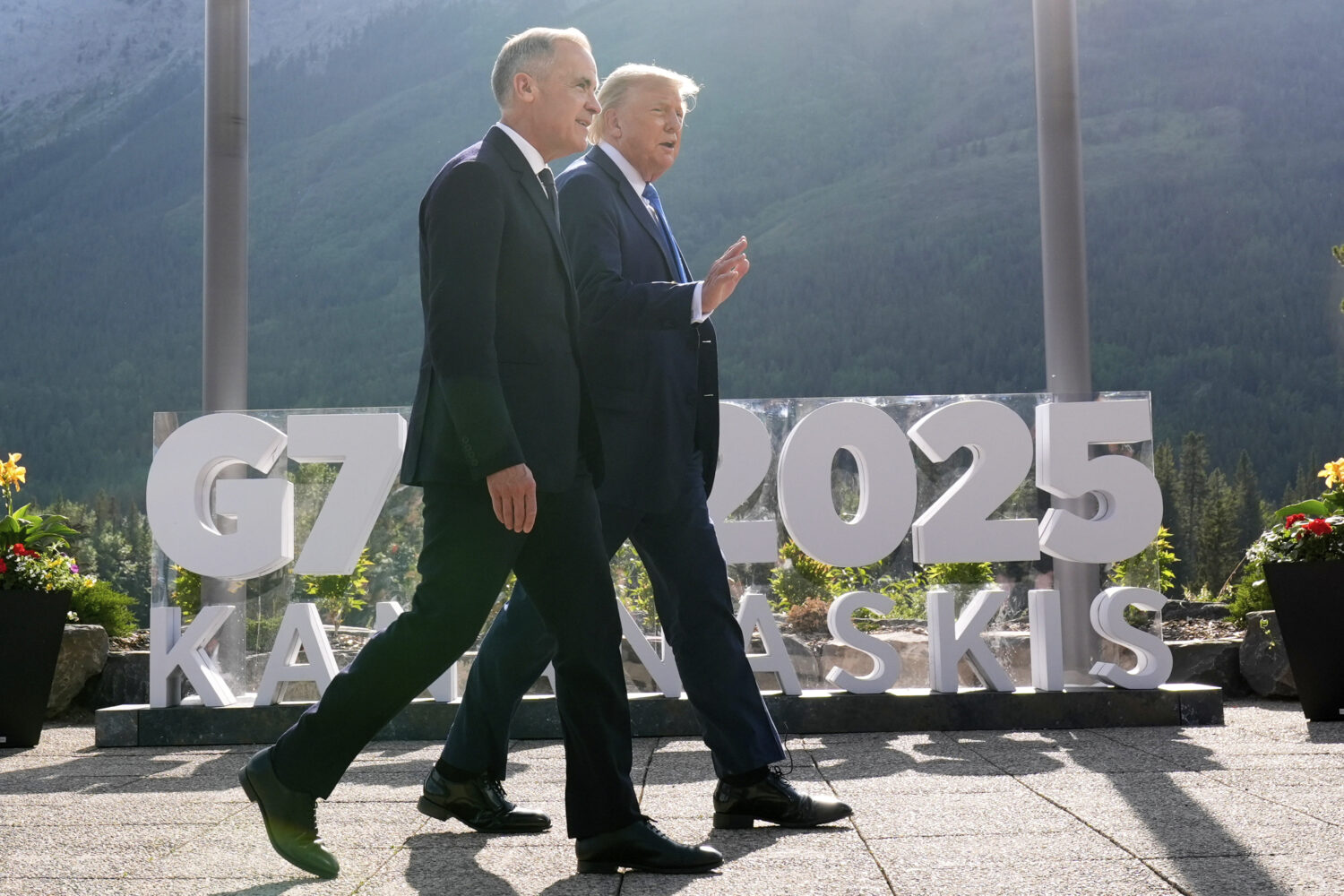 Canada's Prime Minister Mark Carney walks with President Donald Trump after a group photo at the G7...
