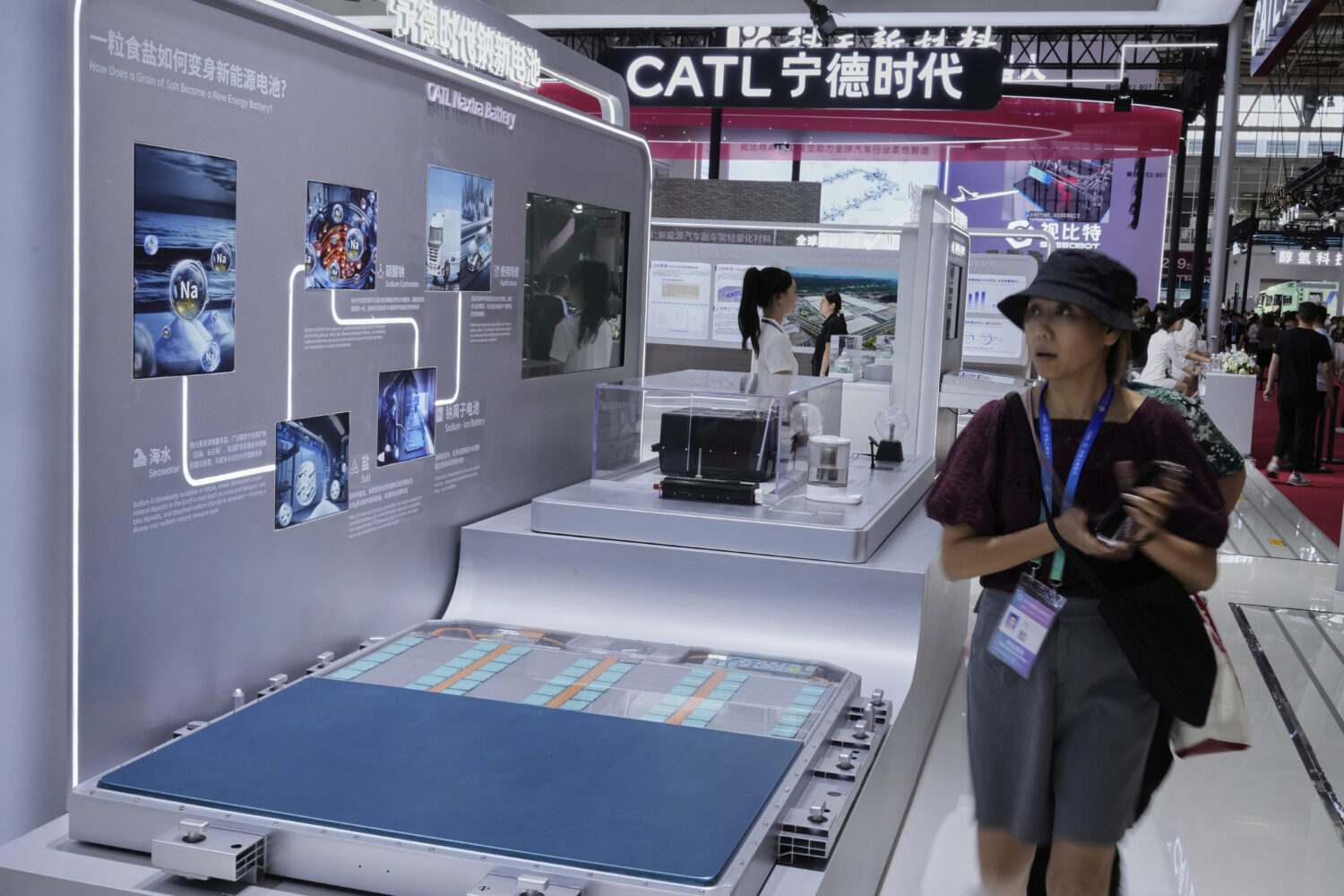 Visitors walk in front of a CATL Naxtra battery is seen at a CATL booth during the 3rd China Intern...