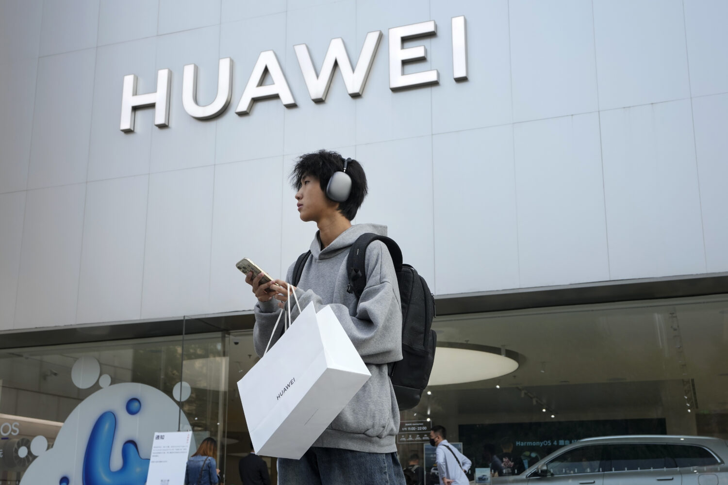 FILE - A customer carries his purchased Huawei product outside a Huawei store after he attended the...