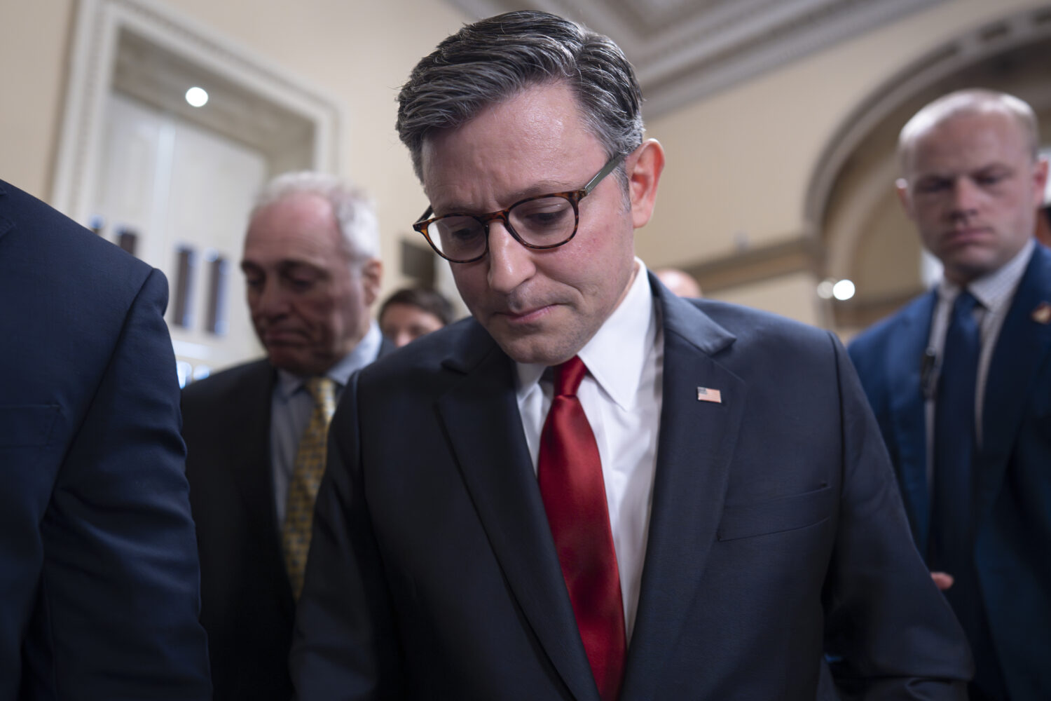 Speaker of the House Mike Johnson, R-La., walks behind his security detail through a crowd of repor...