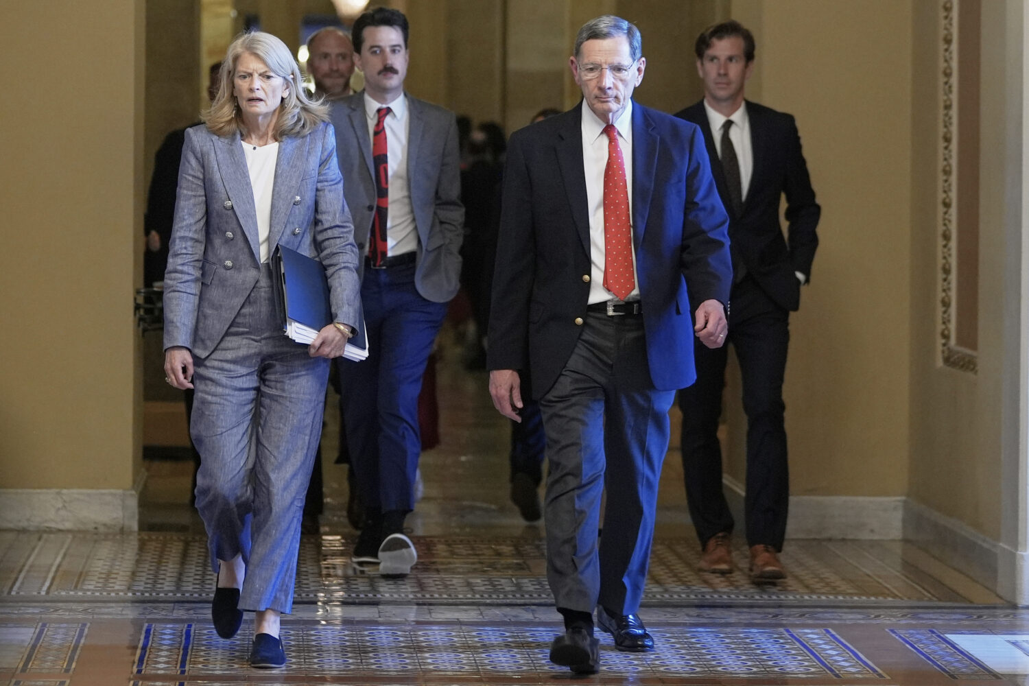 Sen. Lisa Murkowski, R-Alaska, left, and Sen. John Barrasso, R-Wyo., right, walk at the Capitol, Tu...