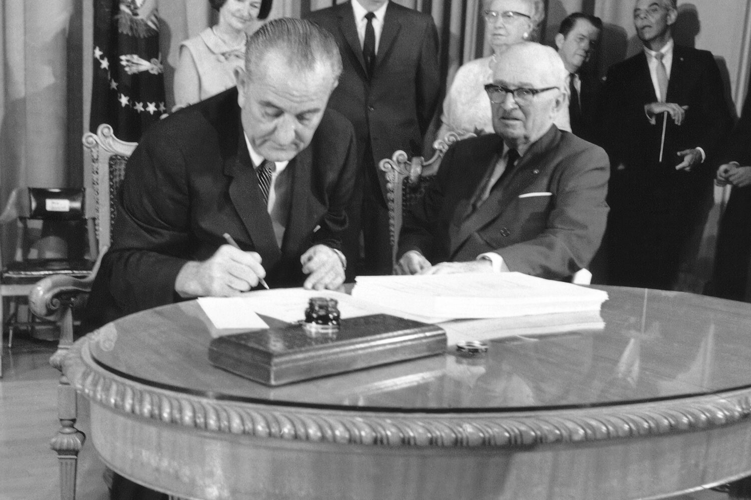 FILE - President Lyndon B. Johnson uses the last of many pens to complete the signing of the Medica...
