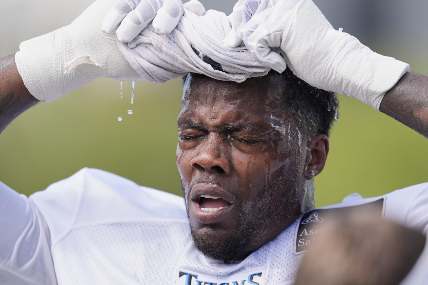 Tennessee Titans linebacker Arden Key uses a wet towel to cool off after practice at the team's NFL...