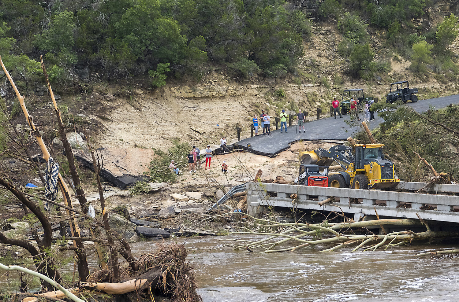 Crews work to clear debris from the Cade Loop bridge along the Guadalupe River on Saturday, July 5,...