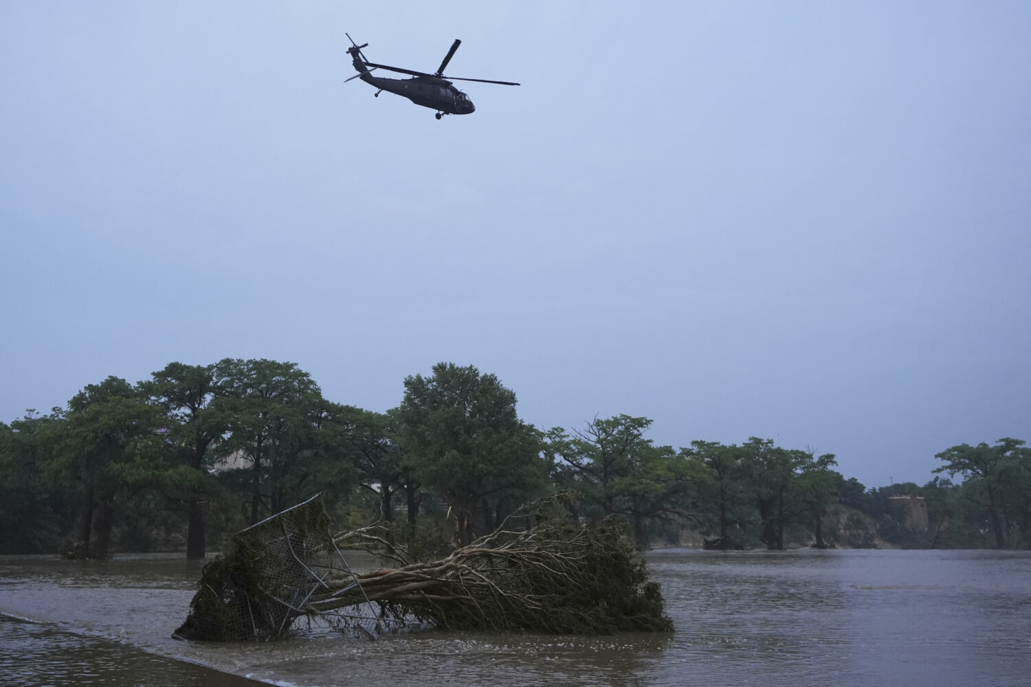 A helicopter flies over the Guadalupe River after a flash flood swept through the area, Friday, Jul...