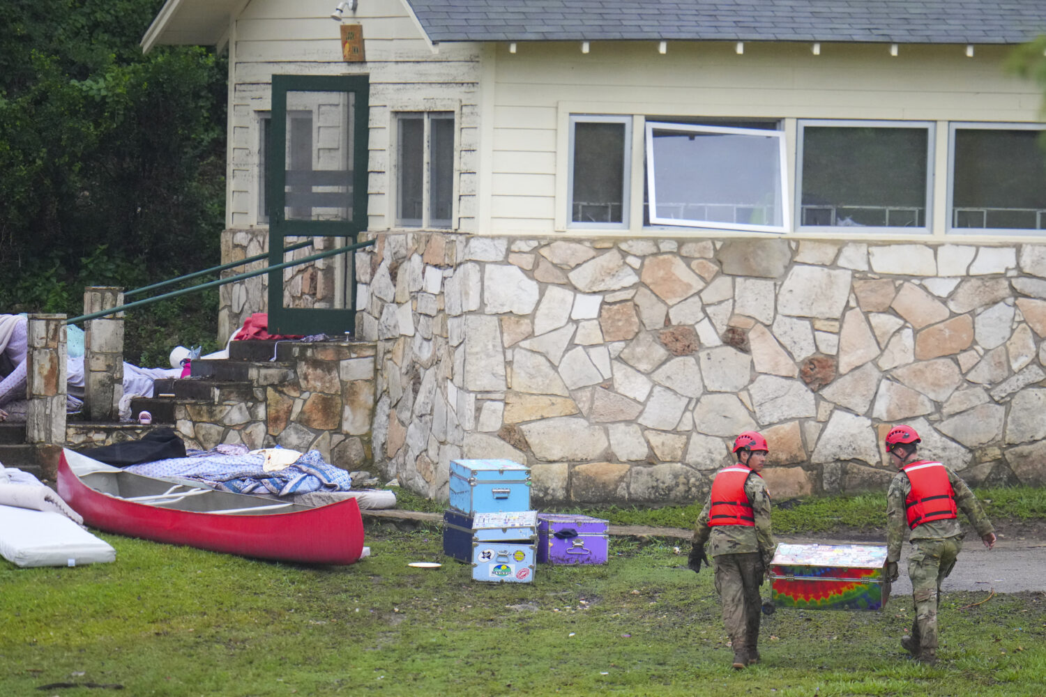 Military personnel return a camp trunk salvaged from down river to Camp Mystic along the Guadalupe ...