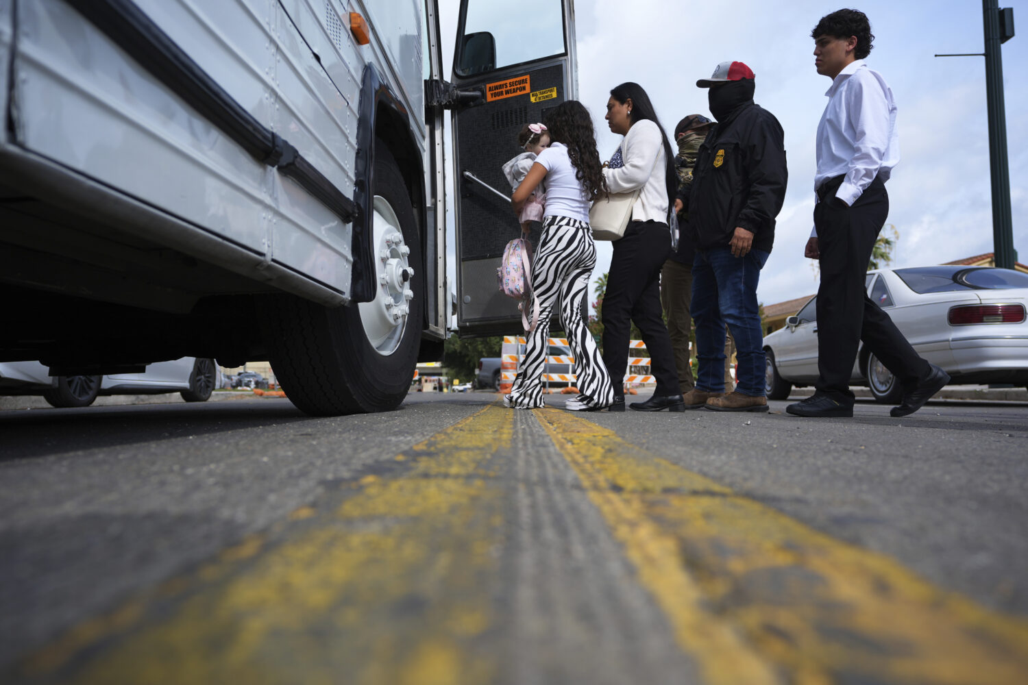 A family from Colombia is detained and escorted to a bus by federal agents following an appearance ...