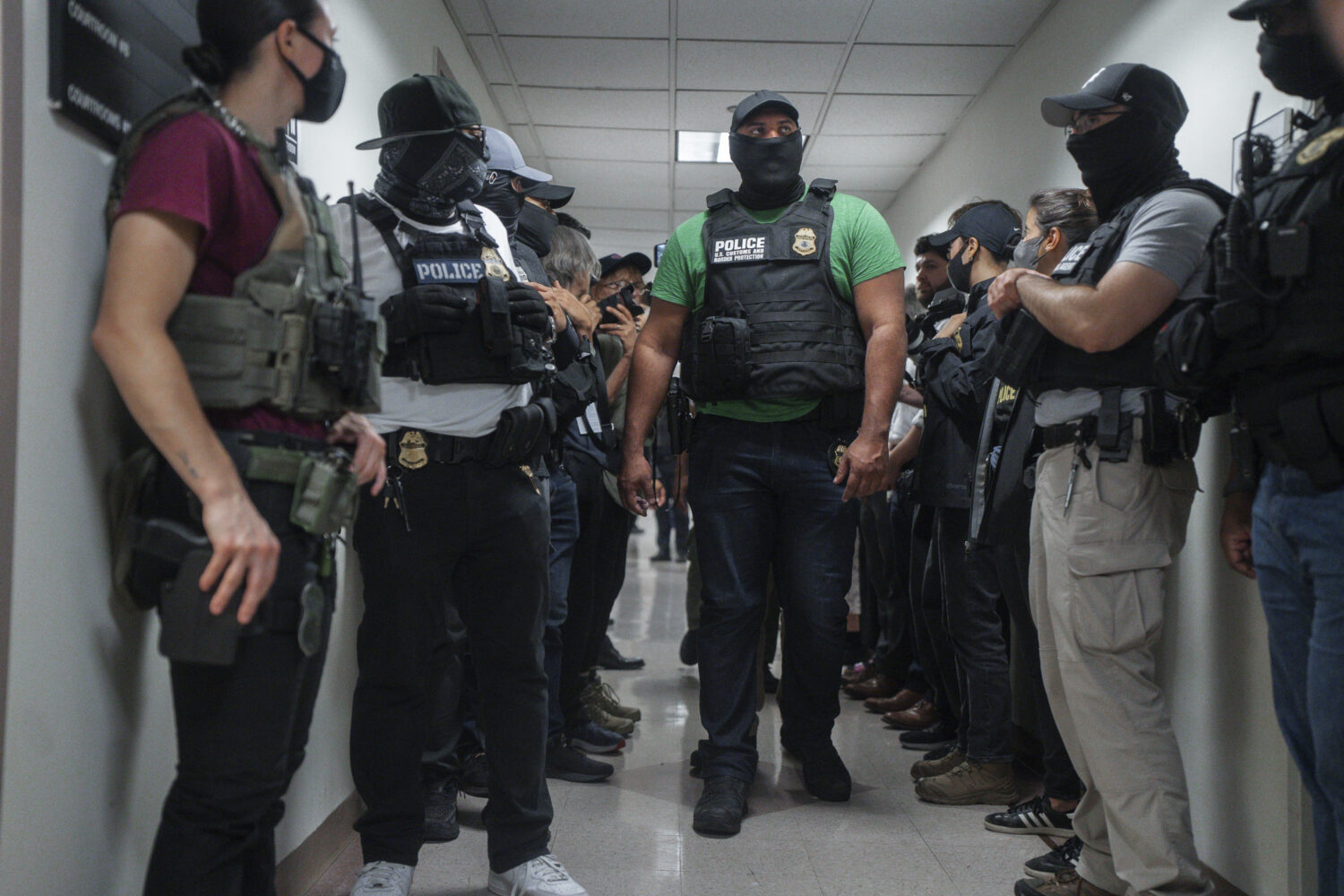 FILE - Masked federal agents wait outside an immigration courtroom, July 8, 2025, in New York. (AP ...