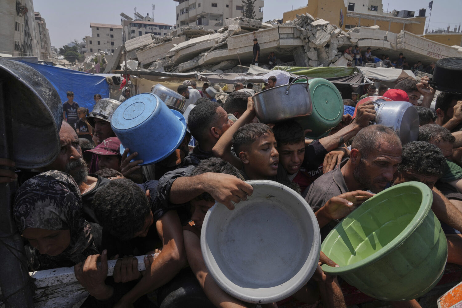 Palestinians struggle to get donated food at a community kitchen, in Gaza City, northern Gaza Strip...
