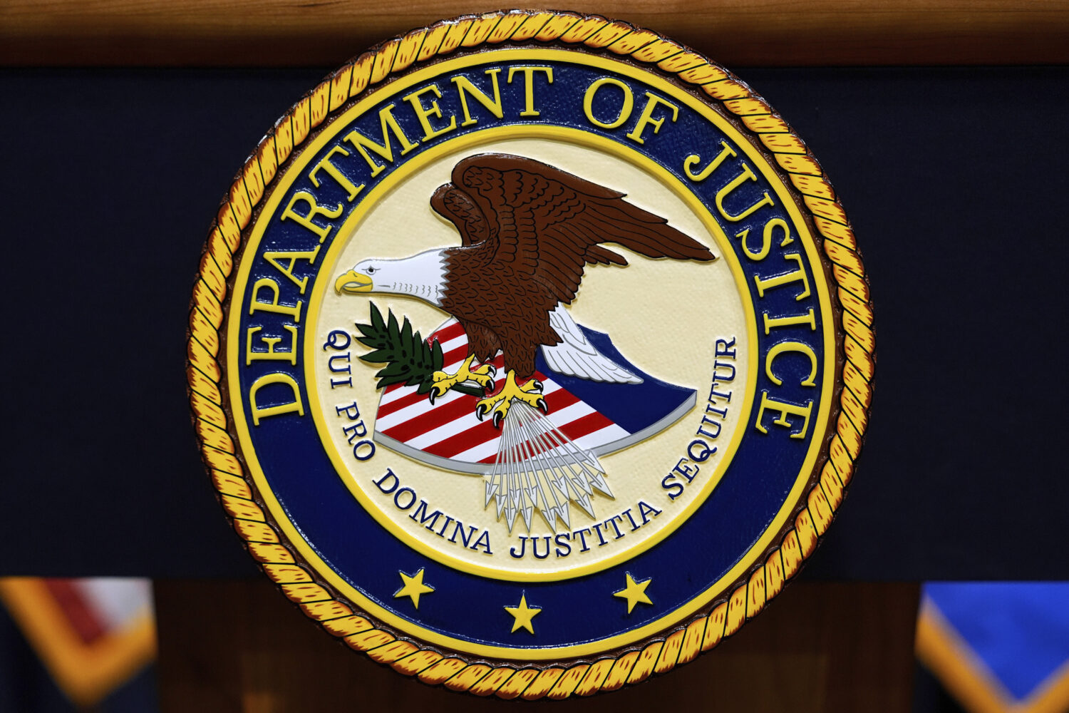 FILE - The U.S. Department of Justice logo is seen on a podium before a press conference, May 6, 20...