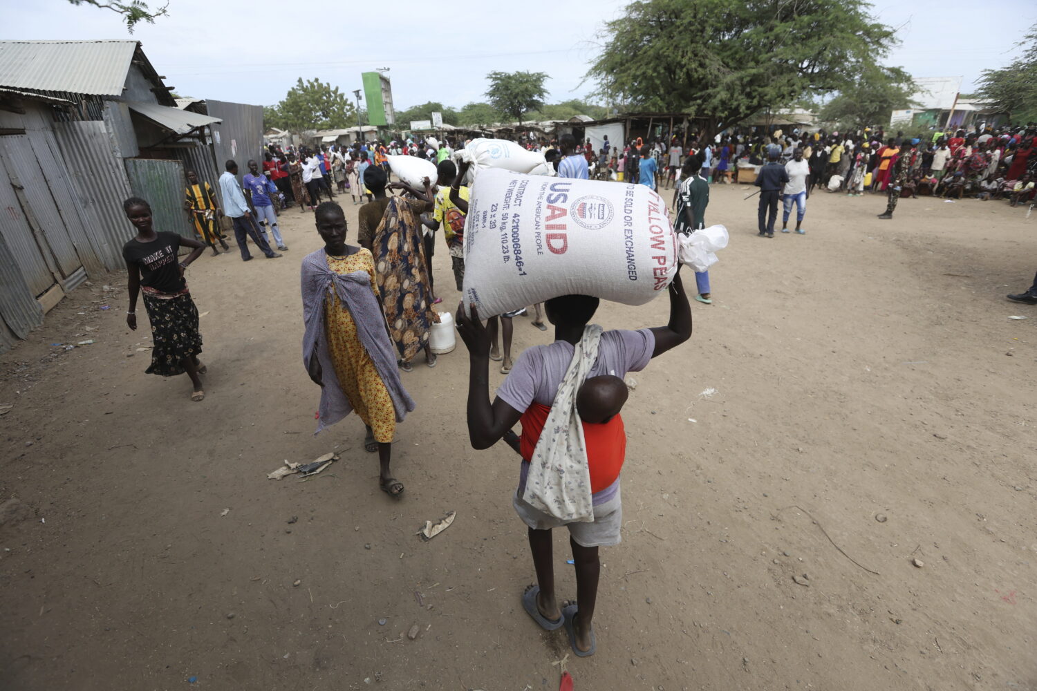 Refugees carry food at a distribution center run by the World Food Programme (WFP) at Kakuma Refuge...