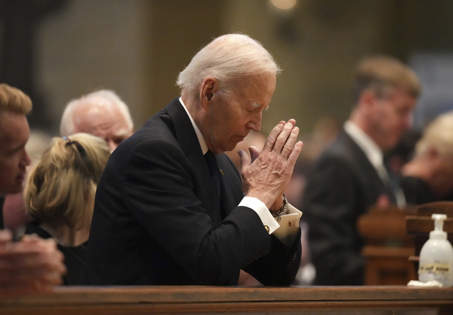 Former US President Joe Biden kneels in prayer during funeral services for Mark and Melissa Hortman...