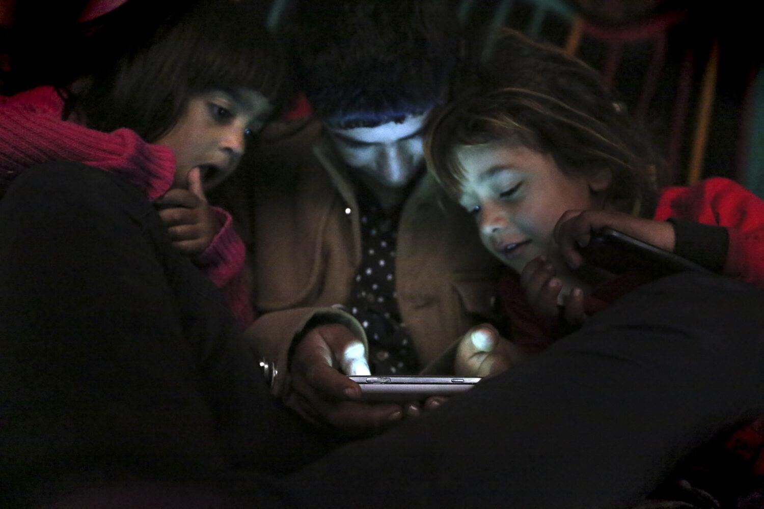FILE - Children from Yazidi families, displaced by Islamic State group militants, look at a smartph...