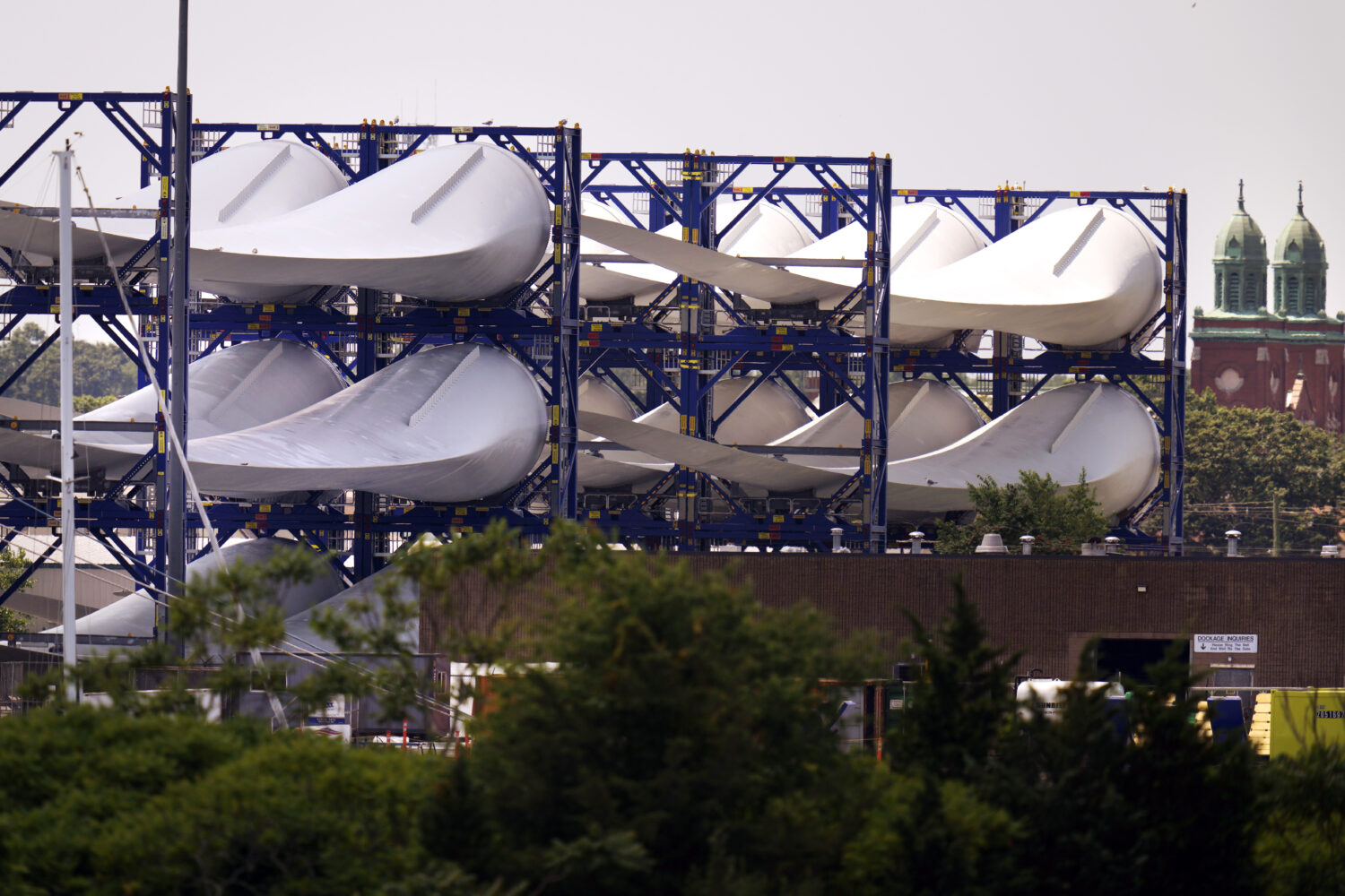 FILE - Giant wind turbine blades for the Vineyard Winds project are stacked on racks in the harbor,...