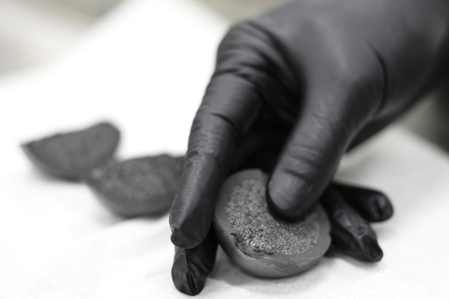 A laboratory worker holds a cross section of TRISO fuel Friday, June 27, 2025, in Oak Ridge, Tenn. ...