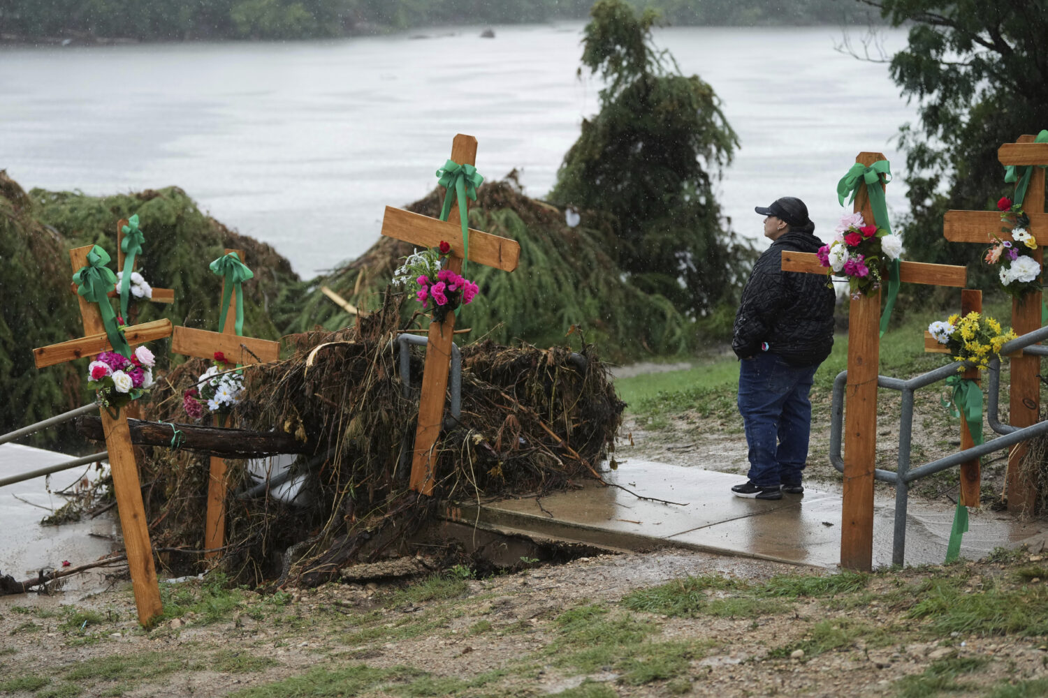 FILE - Rain falls as Irene Valdez visits a make-shift memorial for flood victims along the Guadalup...
