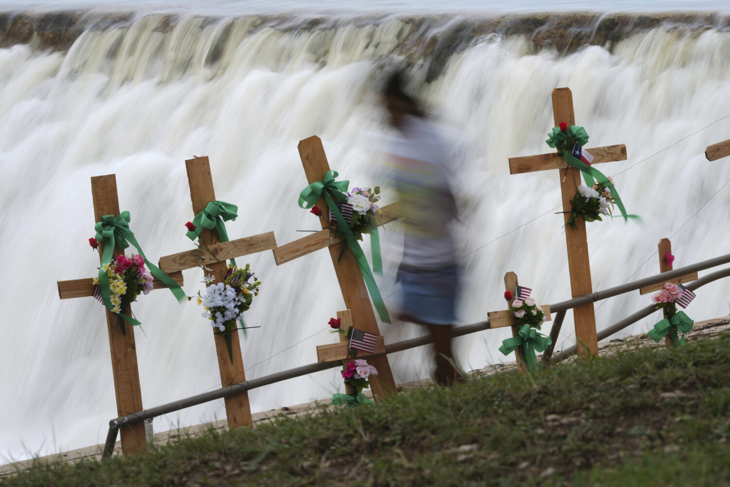 A young girl runs past crosses at a make-shift memorial honoring flood victims, Sunday, July 13, 20...