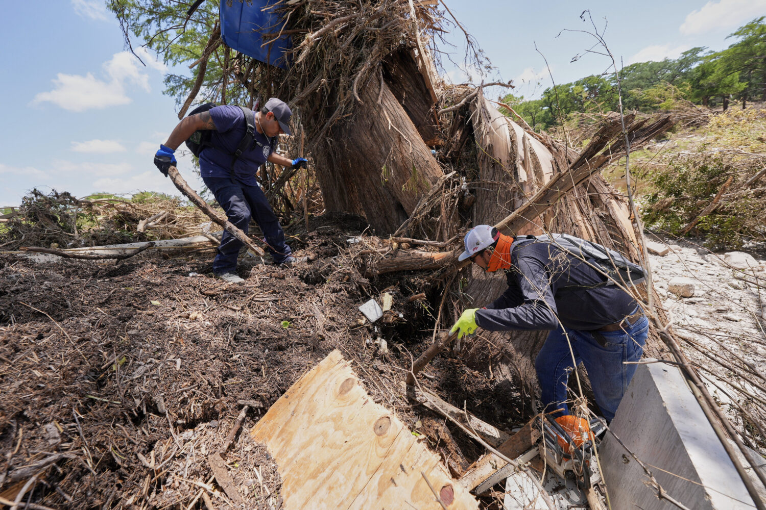 Volunteer Mario Rios, right, and a fellow volunteer, search along the bank of the river after flash...