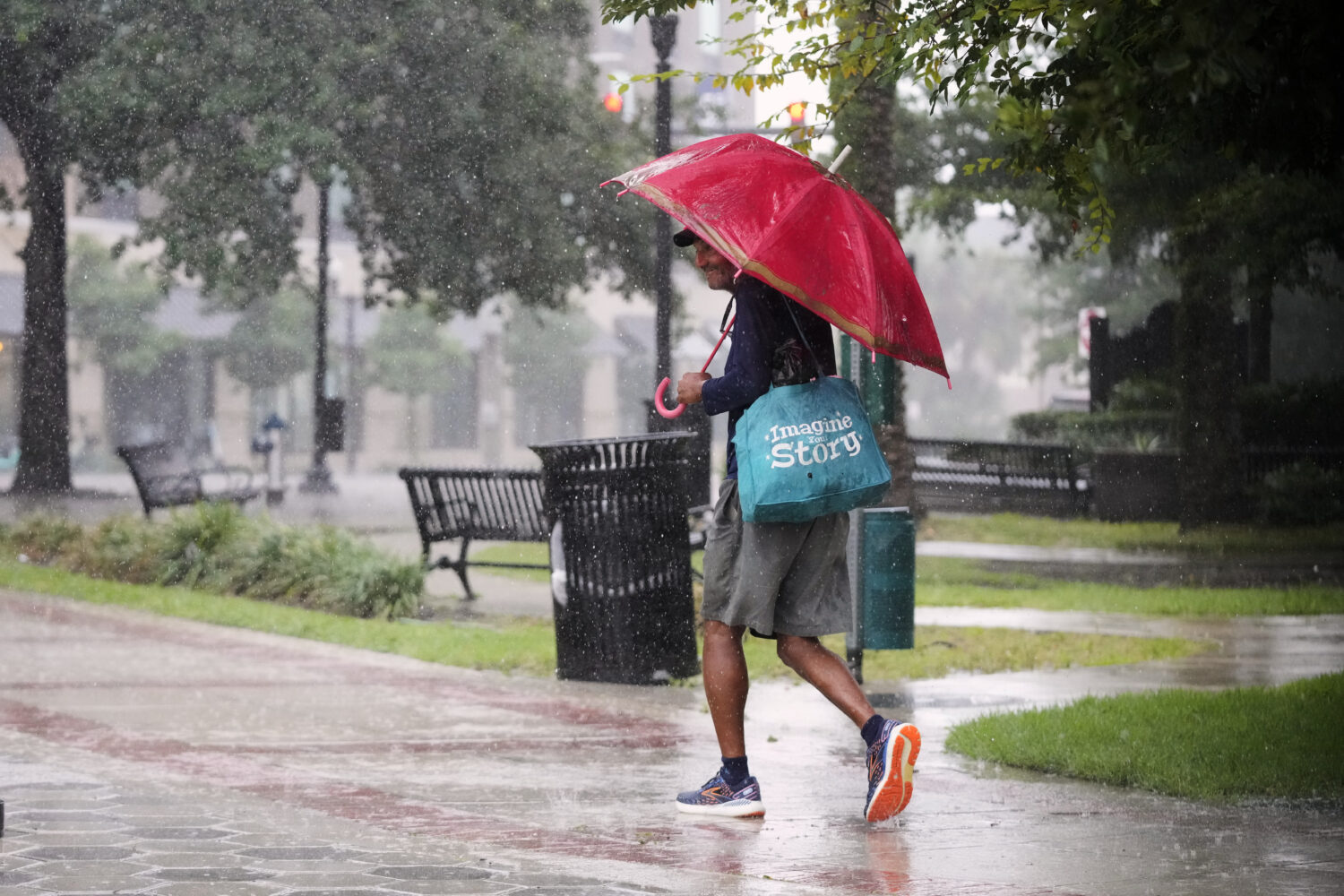A pedestrian walks along a street during a rain shower Tuesday, July 15, 2025, in Orlando, Fla., as...
