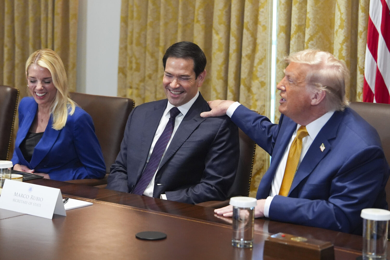President Donald Trump, right, puts his hand on shoulder of Secretary of State Marco Rubio, center,...