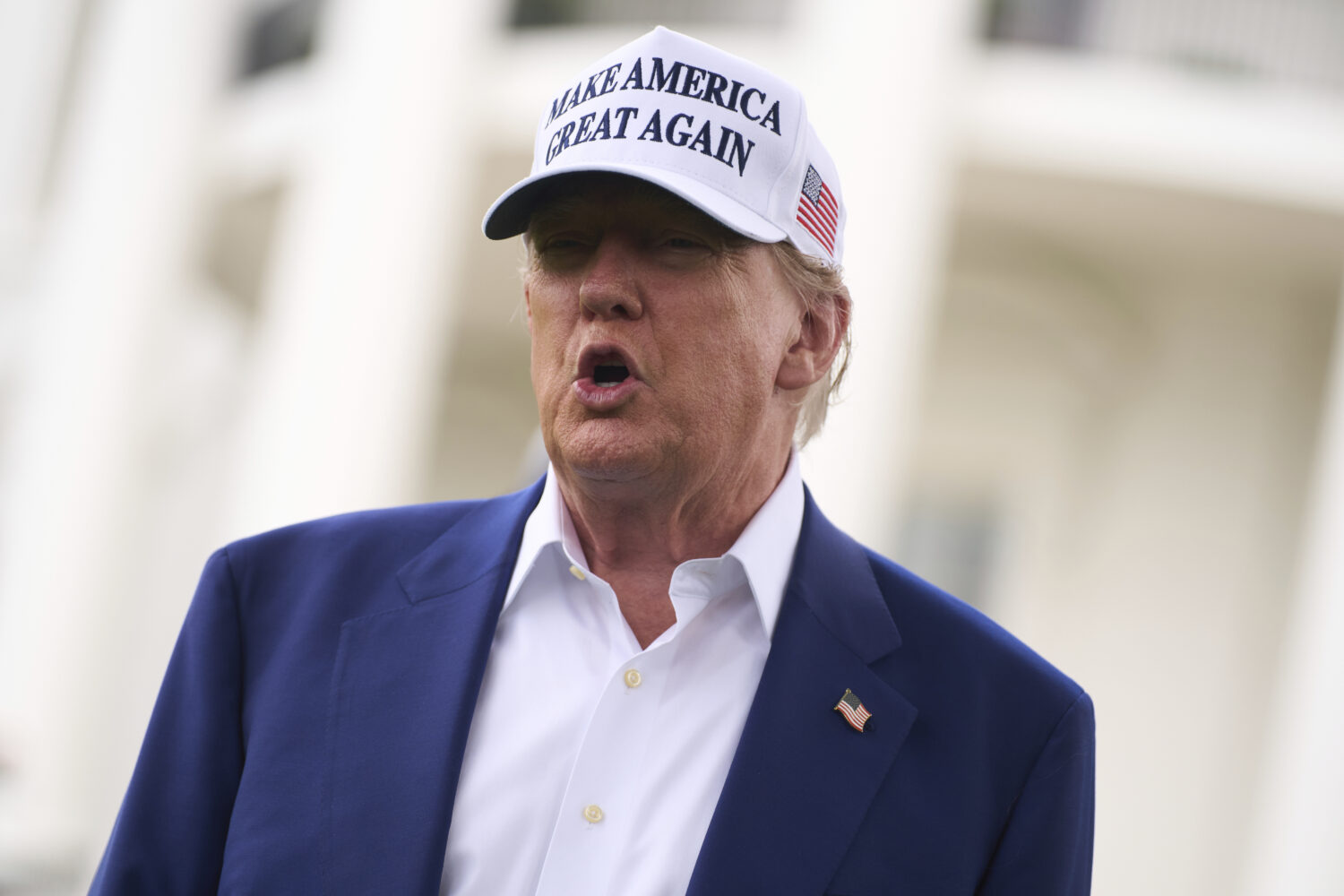 President Donald Trump talks with reporters before a flag pole is installed on the South Lawn of th...