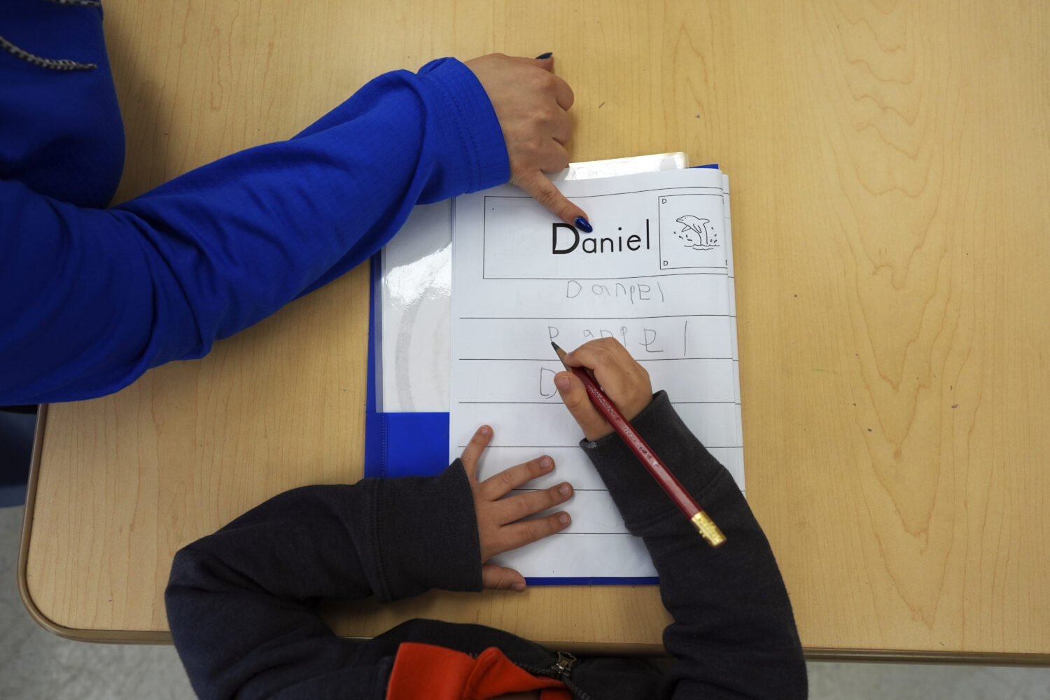 FILE - Easterseals Head Start program teaching assistant Tania Ortiz helps a student practice writi...