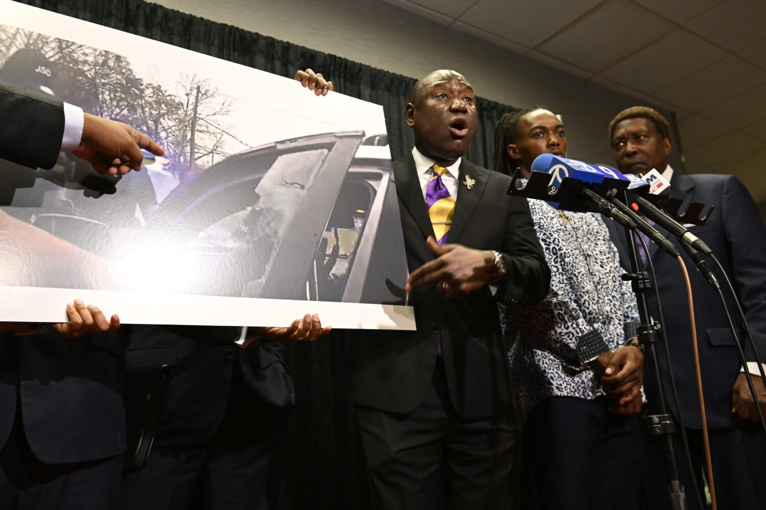 William McNeil Jr.'s attorney Ben Crump, center, speaks while showing a still from a police body ca...