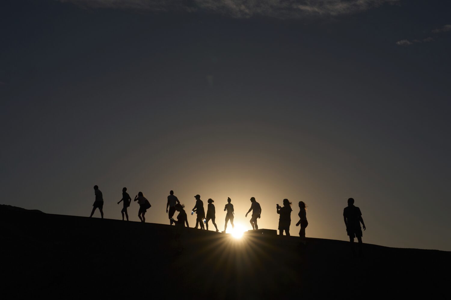 People walk up to an overlook at Zabriskie Point, Sunday, Aug. 3, 2025, in Death Valley National Pa...
