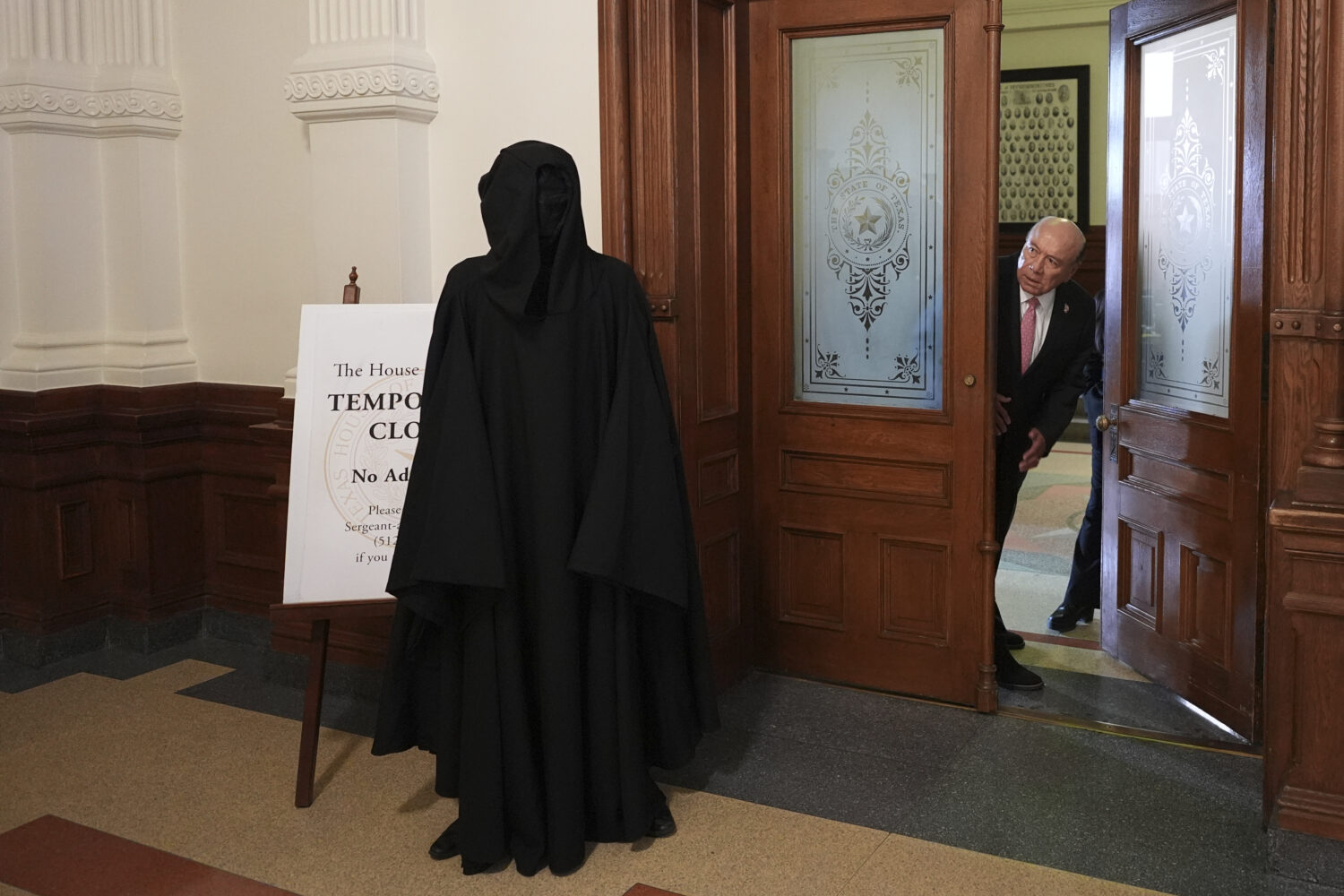 Texas state Sen. Juan "Chuy" Hinojosa, right, looks at a protester dressed as death standing outsid...