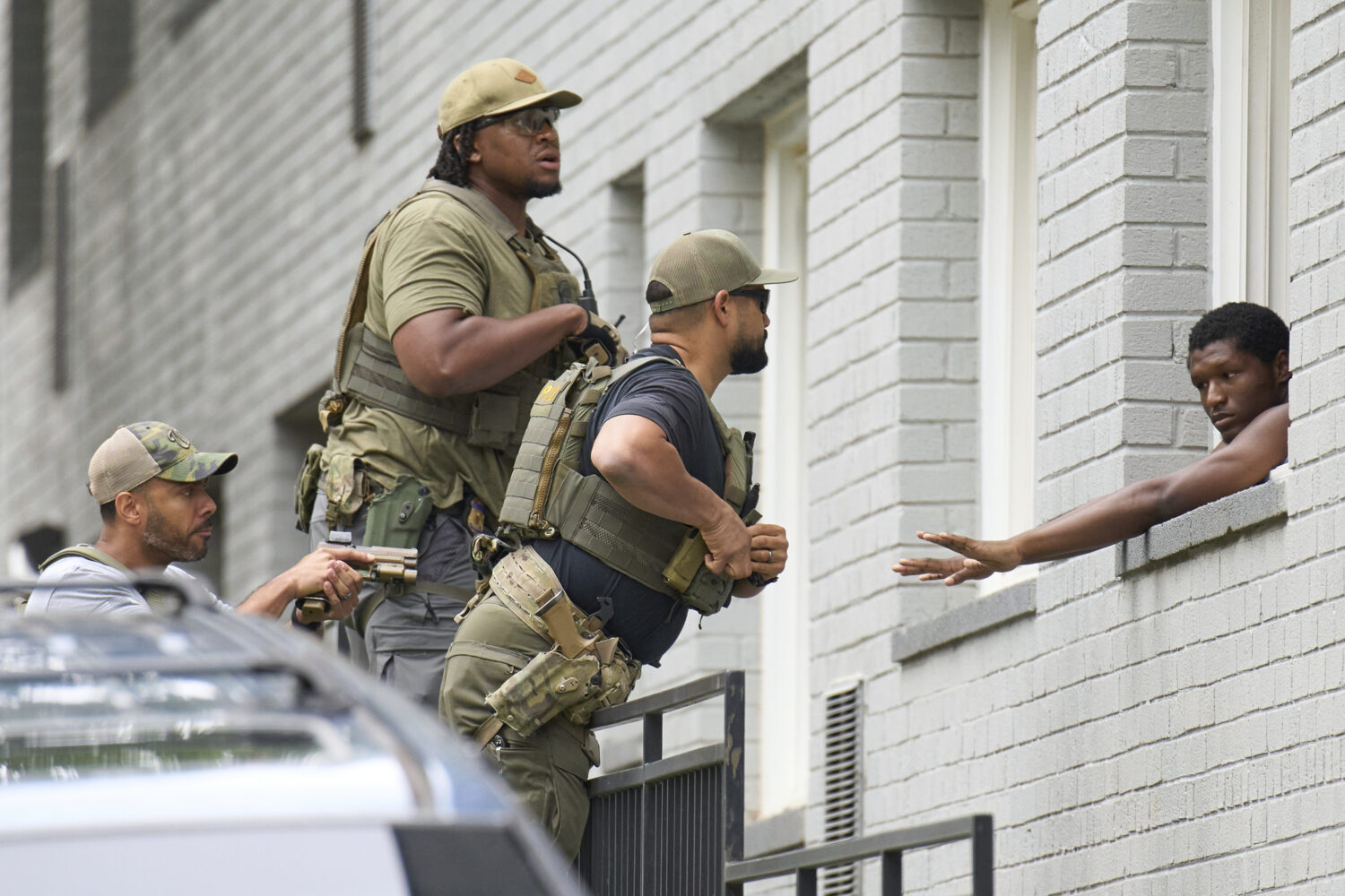 Armed officers prepare to place handcuffs on a man from within an apartment complex, Tuesday, Aug. ...