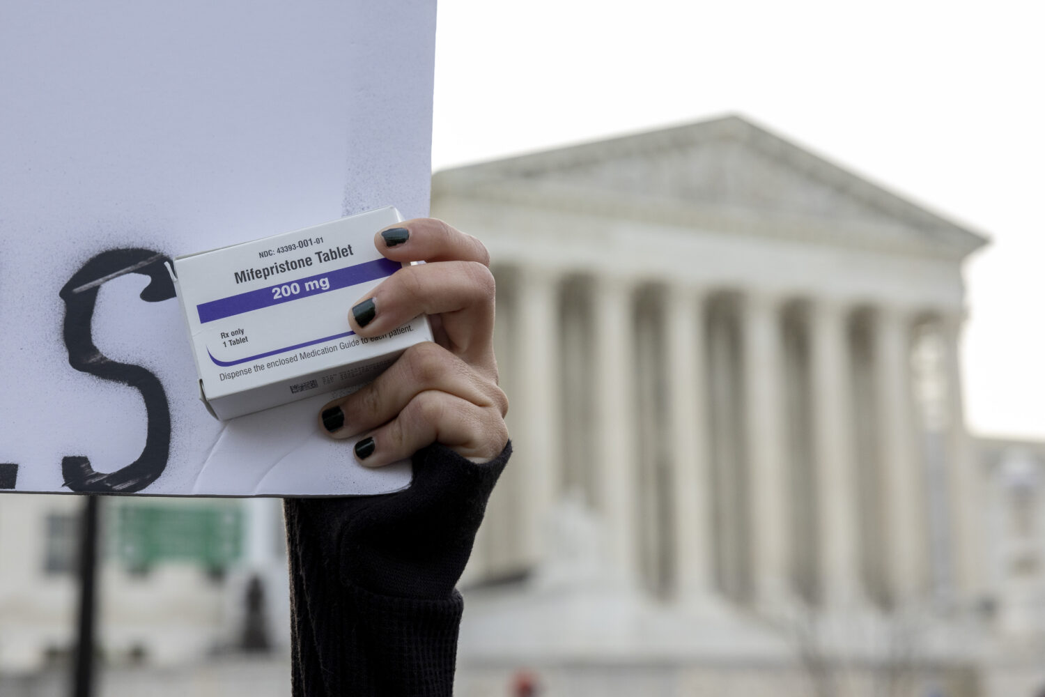 FILE - An abortion-rights activist holds a box of mifepristone pills as demonstrators from both ant...
