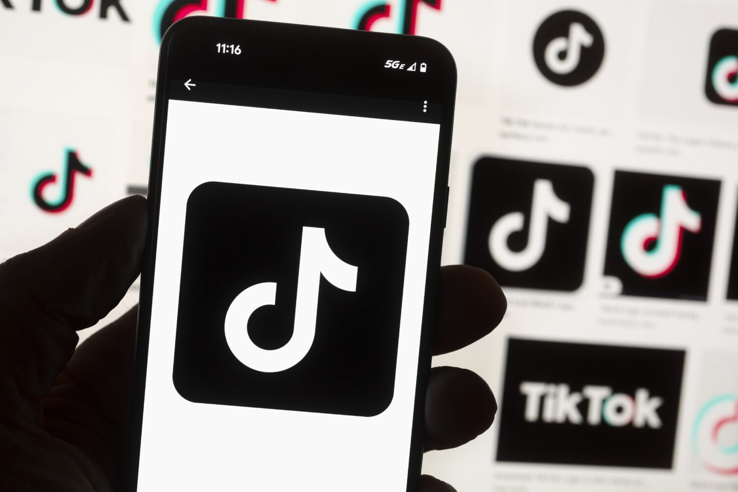 FILE - The TikTok logo is seen on a mobile phone in front of a computer screen which displays the T...