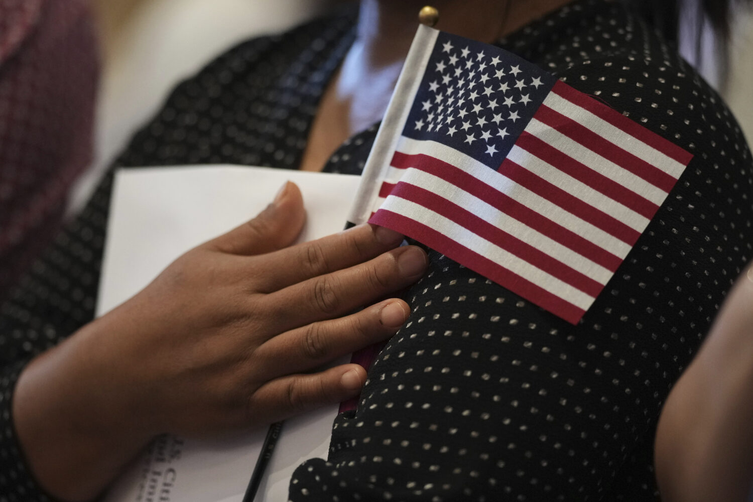 FILE - A woman clutches a U.S. flag as she and applicants from other countries prepare to take the ...